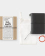 Black travel notebook with packaging and accessories on a white background