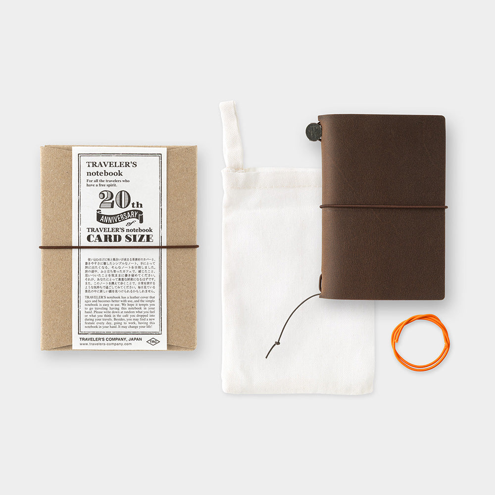 Brown travel notebook with packaging and accessories on a white background
