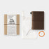 Brown travel notebook with packaging and accessories on a white background