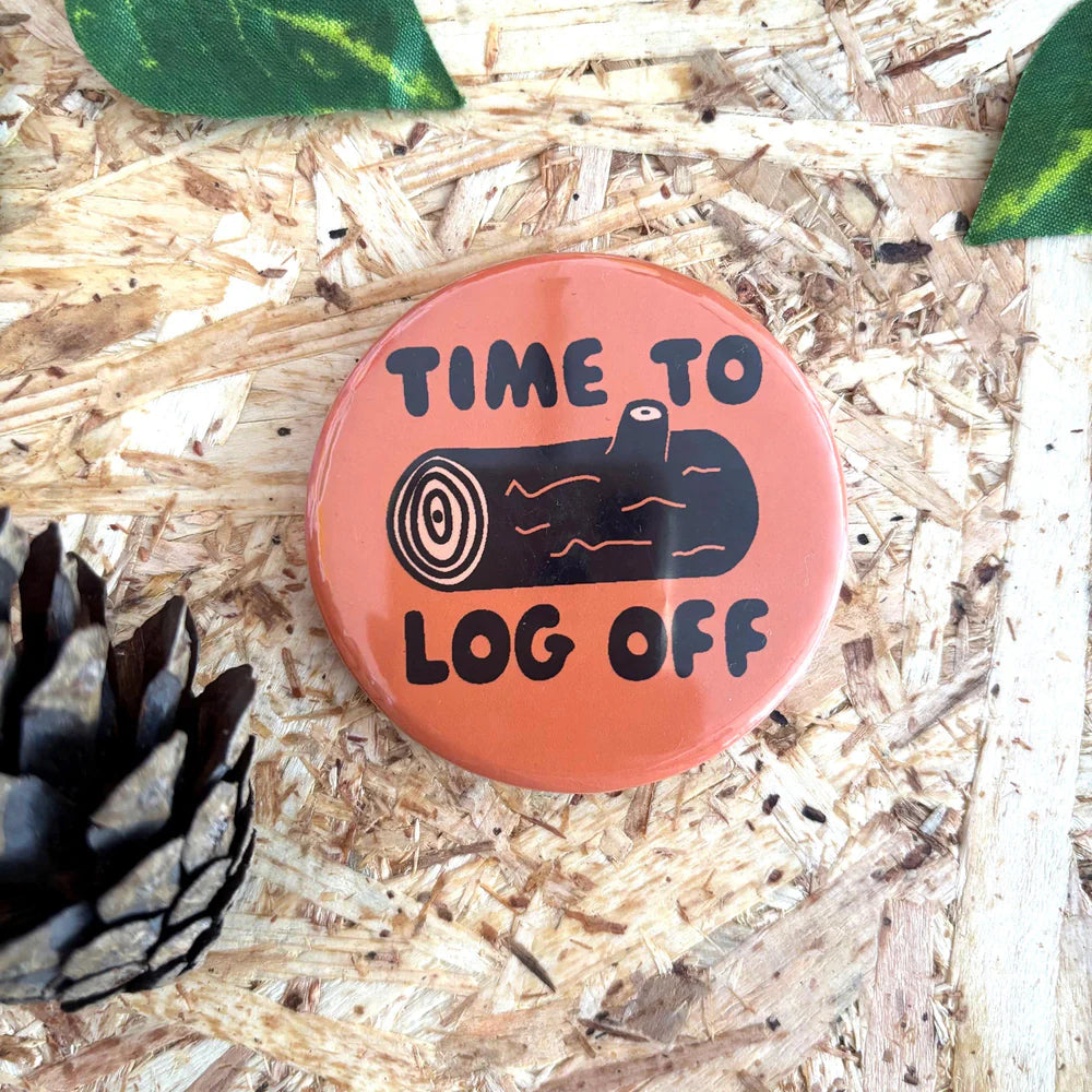 Button badge with 'Time to log off' text on a wooden background