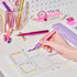 Person using a pink pen on a planner with stationery items in the background