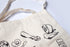 Canvas tote bag with black illustrations of stationery items on a white background