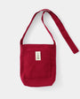 Red shoulder bag with a pocket and strap on a light gray background