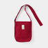 Red shoulder bag with a pocket and strap on a light gray background