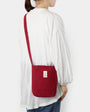 Person wearing a red crossbody bag on a white background