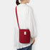 Person wearing a red crossbody bag on a white background