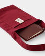 Red fabric pouch with a brown leather wallet inside on a white background