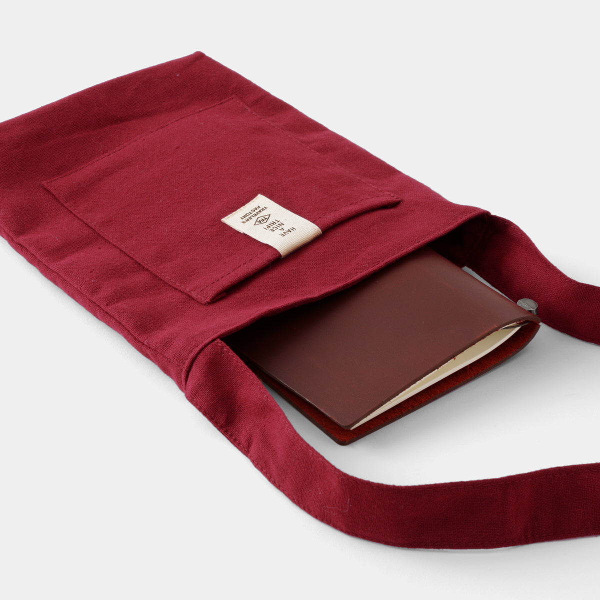Red fabric pouch with a brown leather wallet inside on a white background
