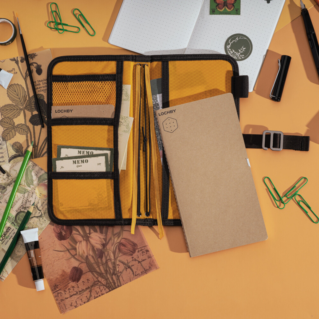 Organized stationery items including a notebook, pen, and paper clips on an orange background.