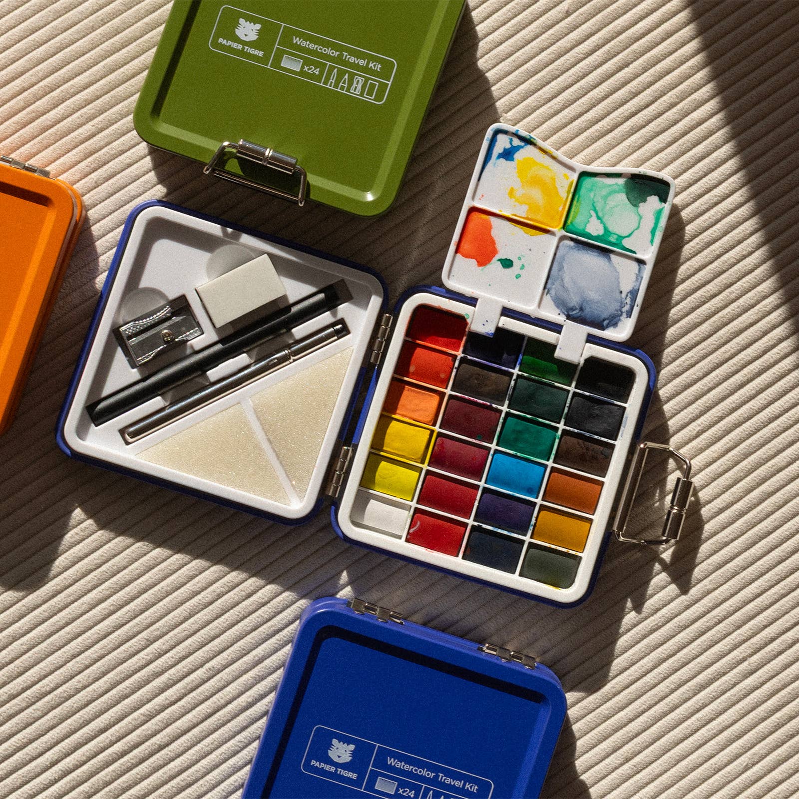 Watercolor paint sets in various colors on a textured surface