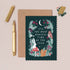 Greeting card with floral design and text, envelope, and pen on a beige background