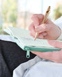 Person writing in a notebook with a pen outdoors