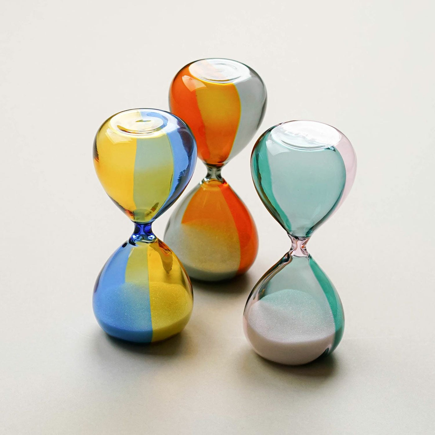 Three colorful hourglass-shaped objects on a light background