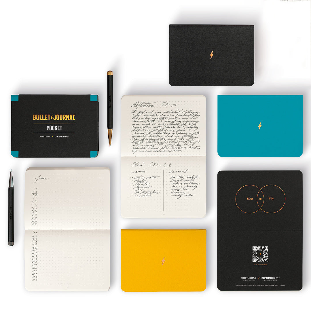 Collection of bullet notebooks and a pen on a white background