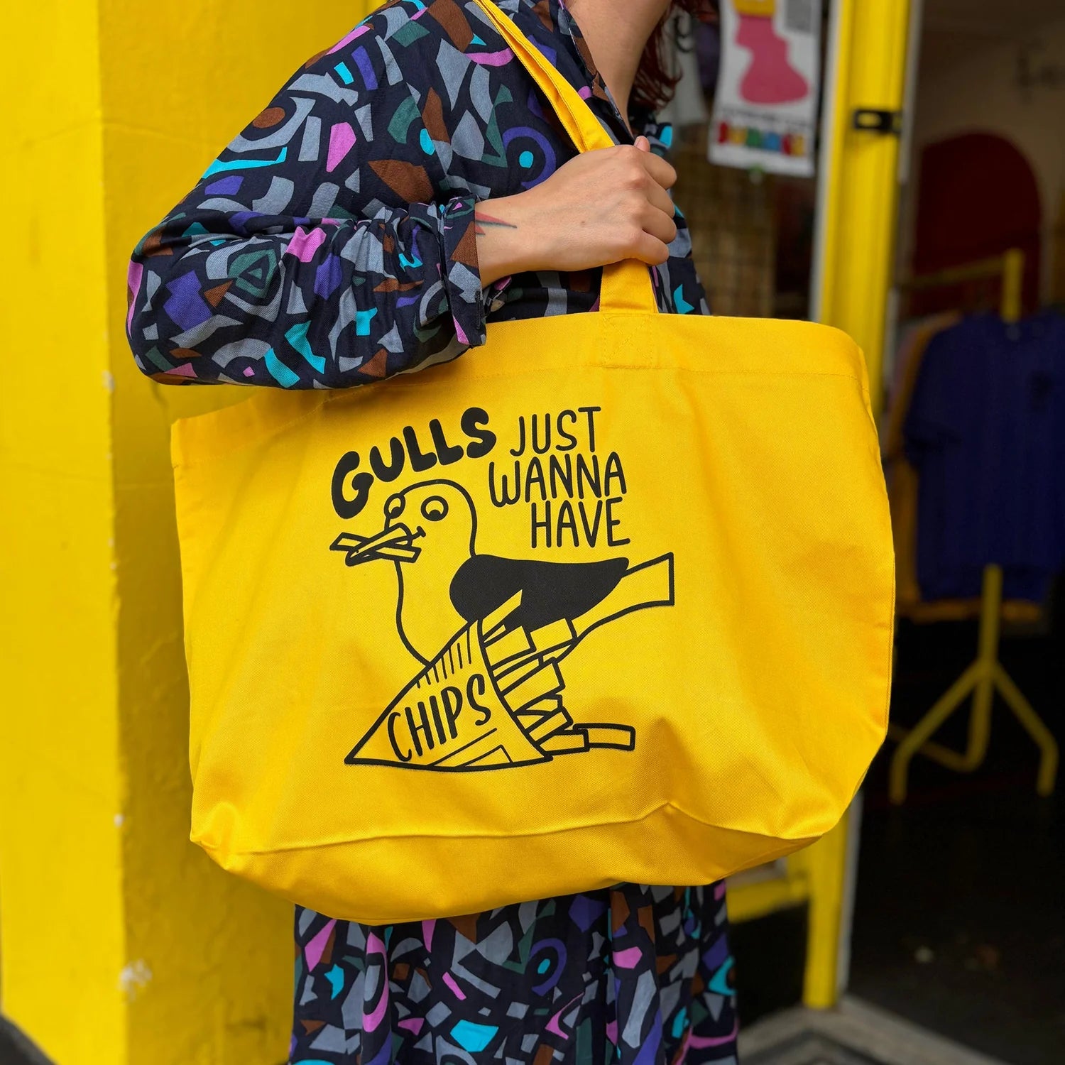 Person holding a yellow tote bag with a graphic design and text.