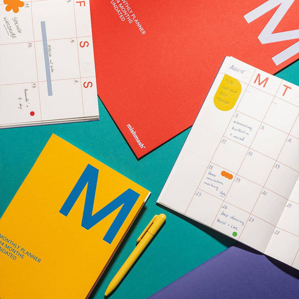 Colorful planner books with a pen on a teal background