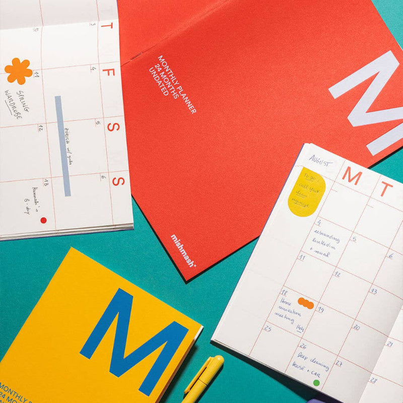 Colorful planner books with a pen on a teal background
