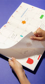 Person holding a planner with colorful stickers on a blue background
