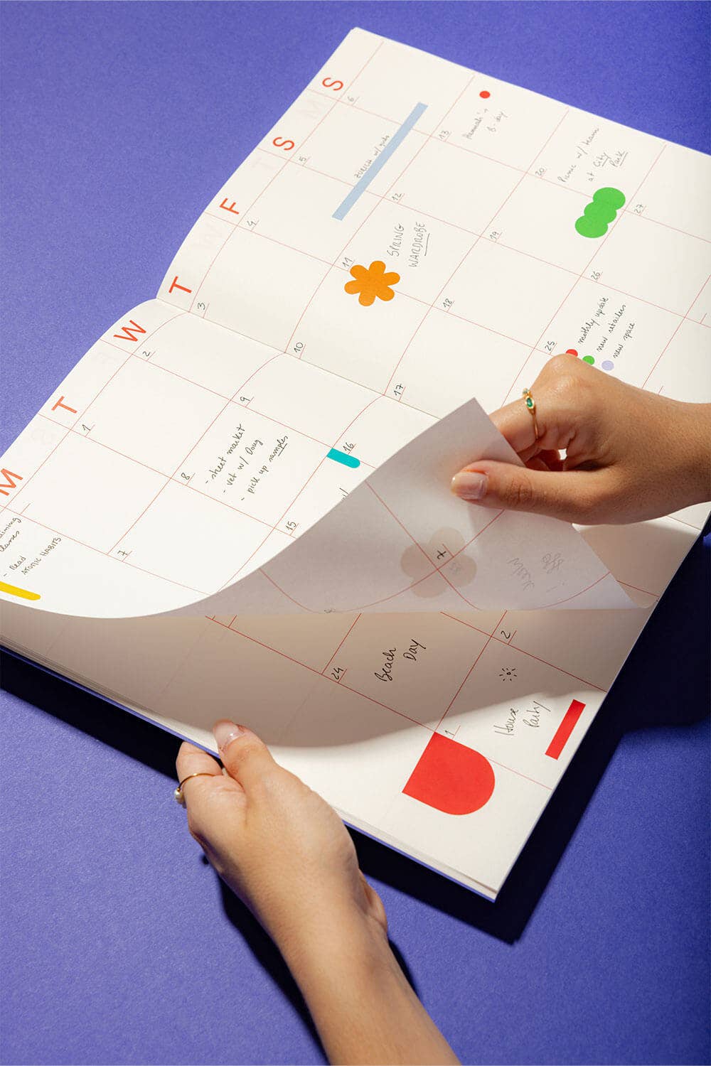 Person holding a planner with colorful stickers on a blue background