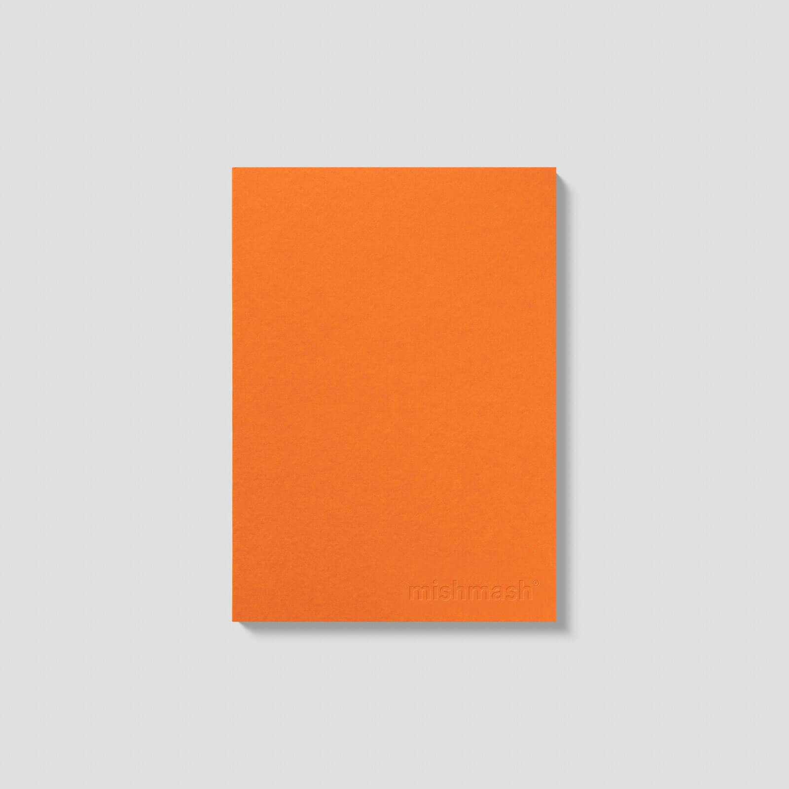Orange notebook with 'mismast' branding on a light gray background