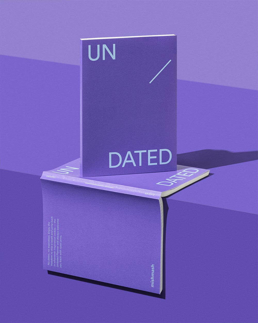 Purple notebook with 'UN' and 'DATED' text on a reflective purple surface