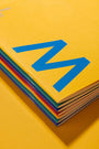 Stack of colorful books with a blue logo on a yellow background