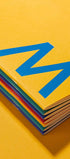 Stack of colorful books with a blue logo on a yellow background