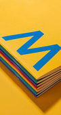 Stack of colorful books with a blue logo on a yellow background