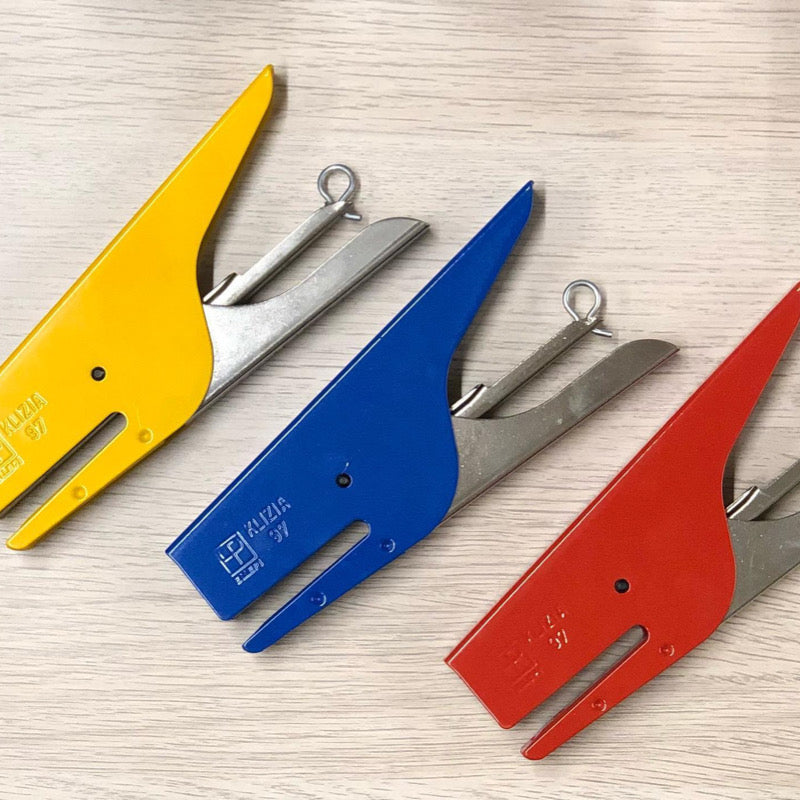 A set of four handheld staplers in red, blue, yellow, and silver colors, laid out on a surface.